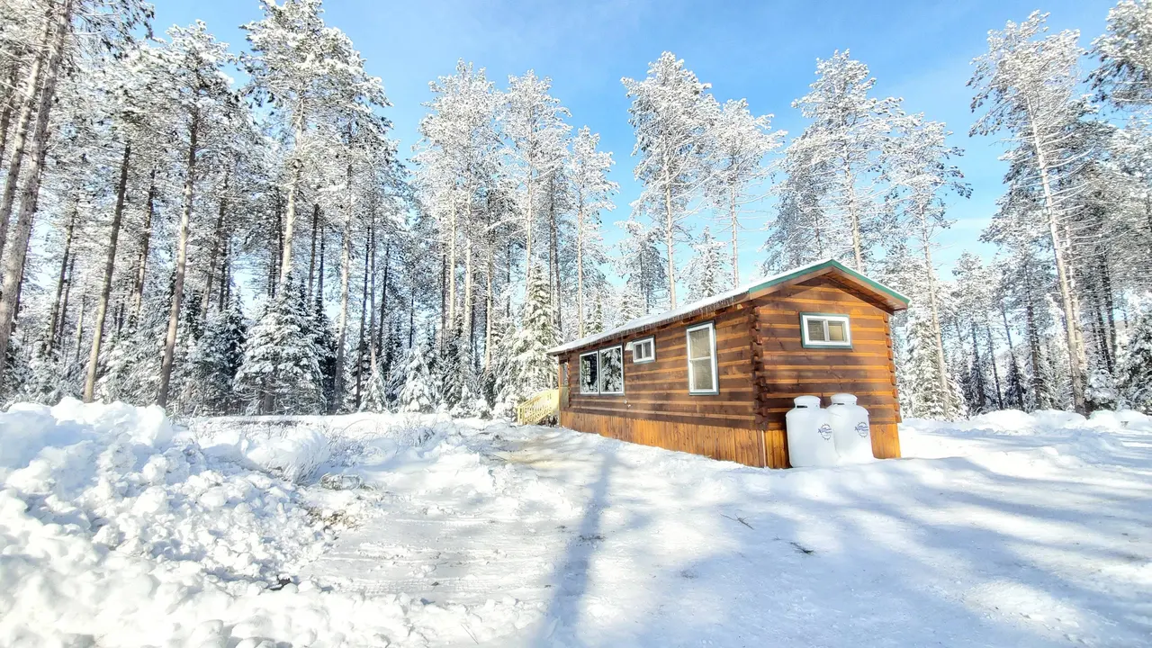 The Modern Tiny Home in deep snow under a blue sky