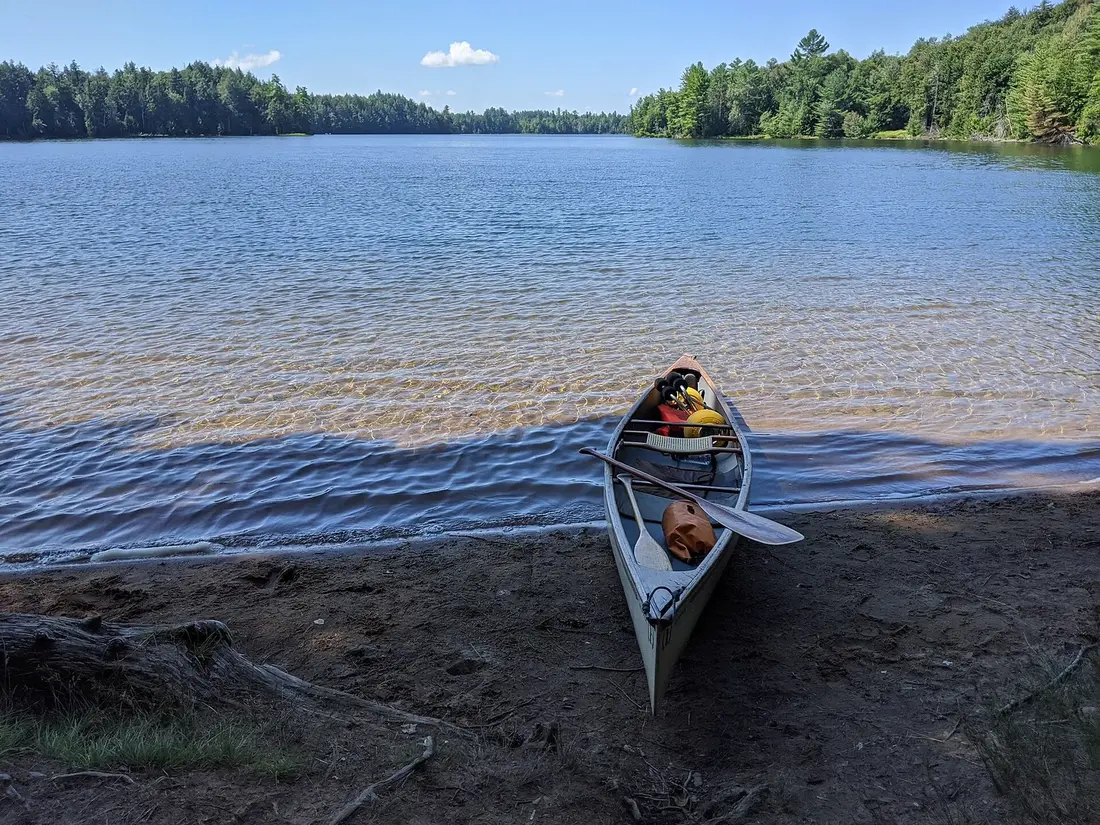 A canoe pulled up on the shore of a pond in the Saint Regis Canoe Area