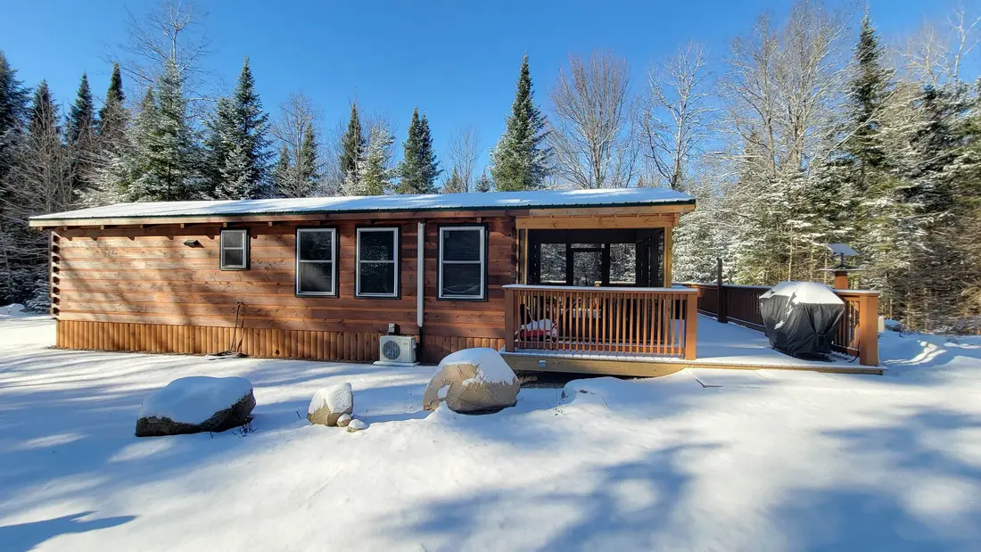 The Modern Pine in the snow, with the screened room on the deck and the grill under its cover