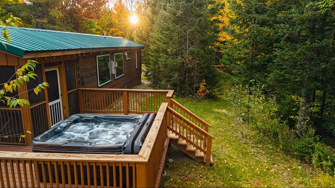 The Modern Pine's hot tub on its deck at golden hour, with the forest behind