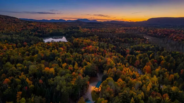 Sunset over the forest and the mountains, seen from the air above the cabins